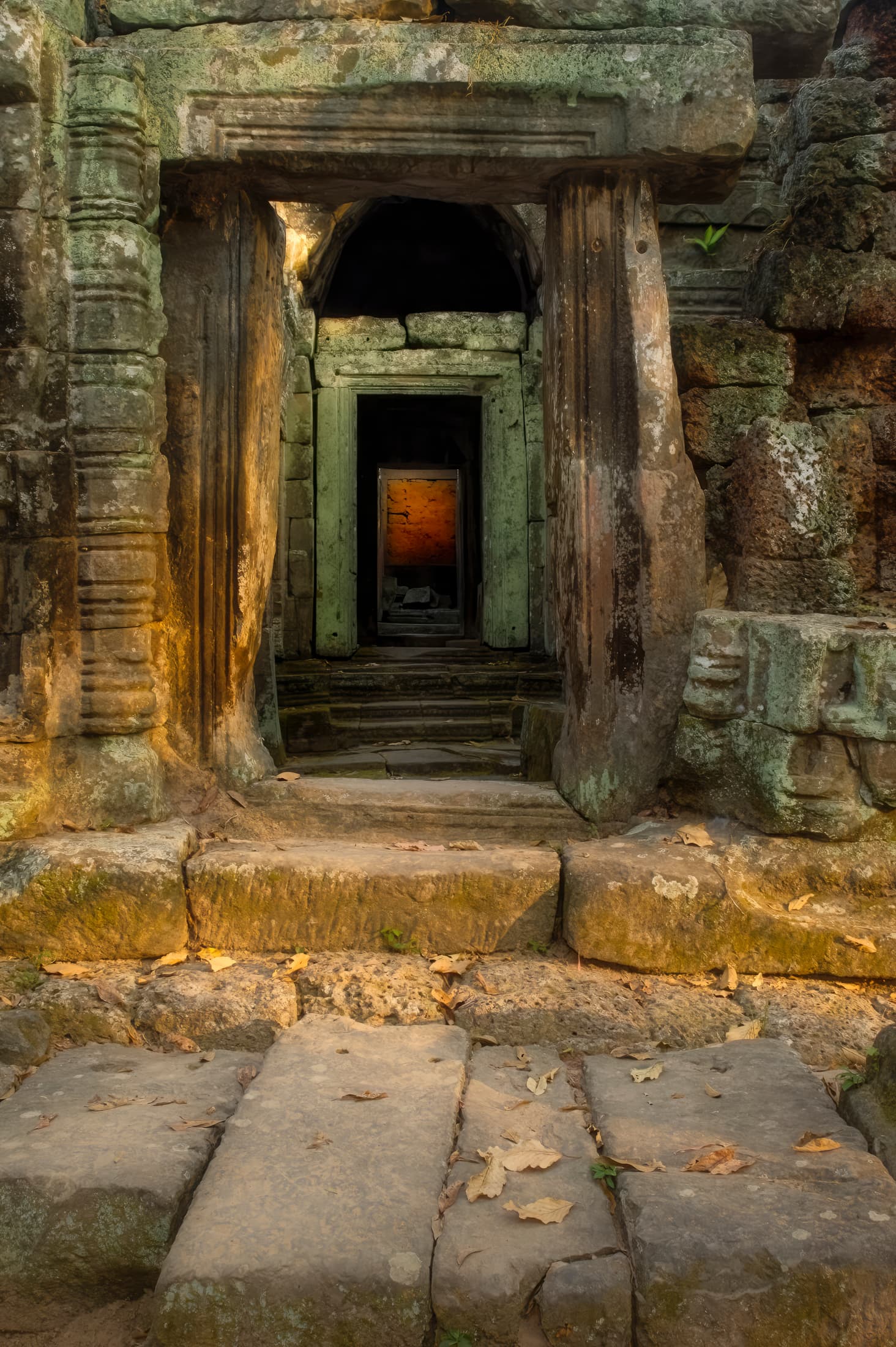 Angkor Archeological Park, Siem Reap, Cambodia. Framed view through multiple doorways and ancient blocks of stone to glowing inner sanctum of Banteay Kdei Temple.