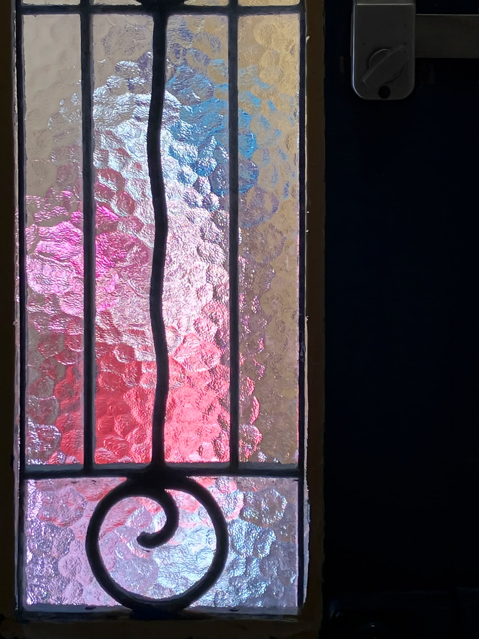 Collioure, France. Door with textured glass and wave icon. Outside passersby create abstract pastel-colored forms.