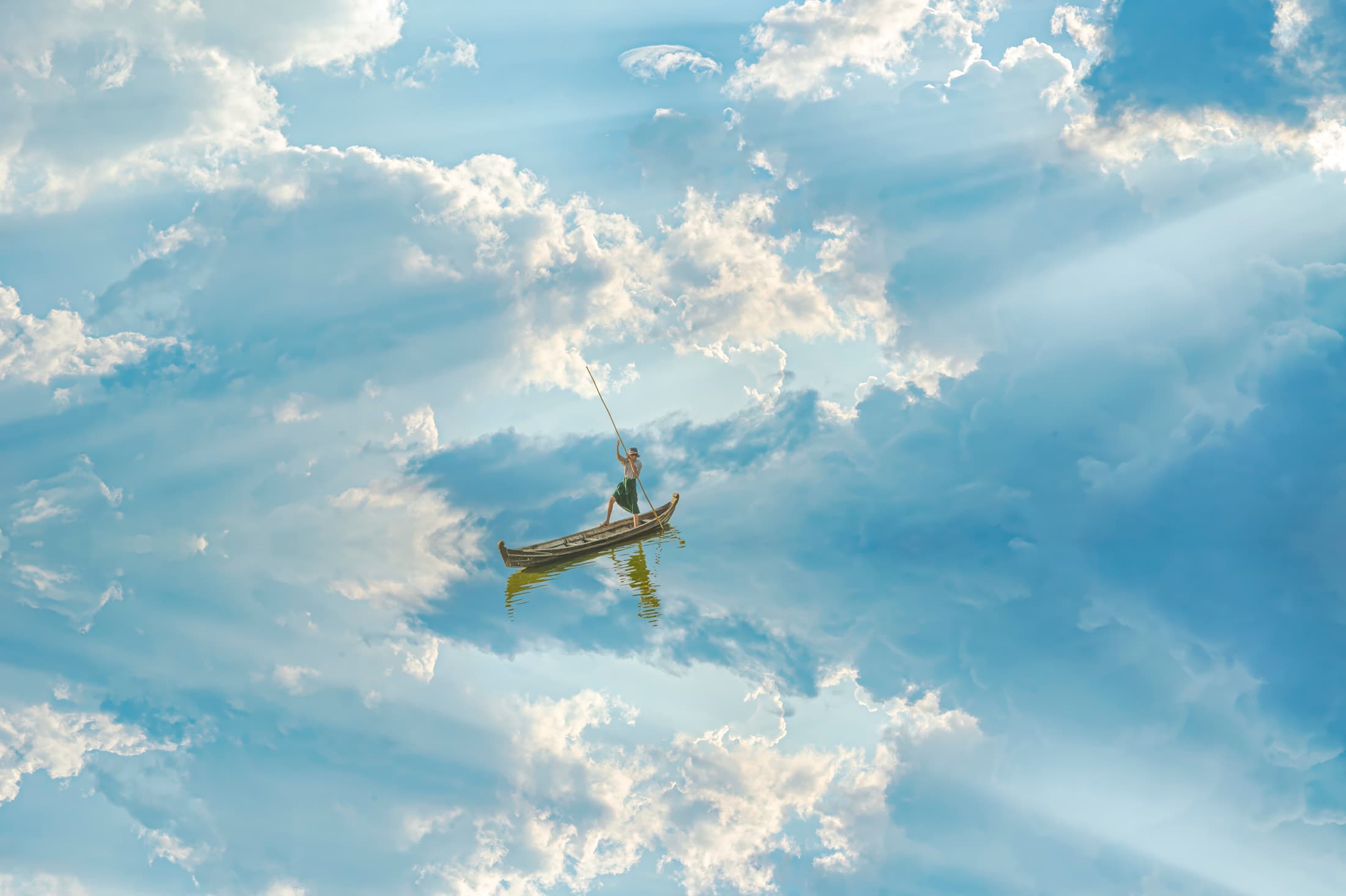 Lone person in a traditional canoe-like Burmese boat traveling in the sky through clouds,  reflections, and streaming light. Composite.