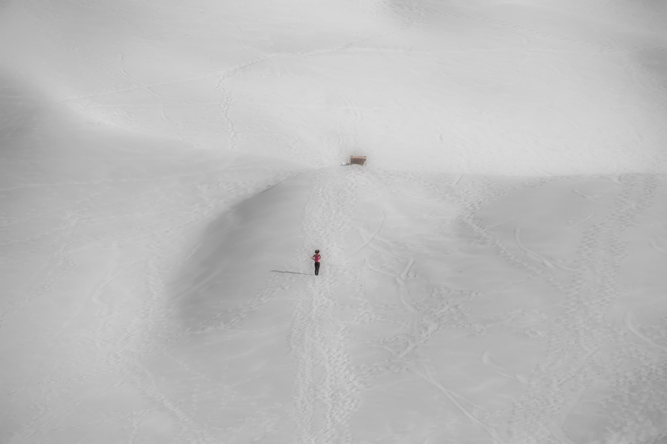 La Huacachina, Ica, Peru. Solitary person pauses while walking on vast white sand dunes. Symbolic of journey.